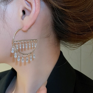 Close-up of silver geometric semi-circle earrings with dangling crystal fringes on model