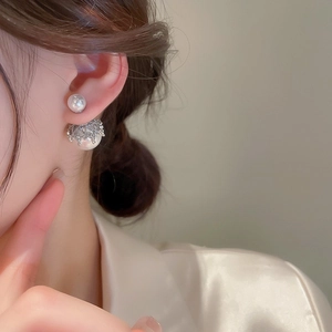Detail of silver pearl double-sided earrings on a model with an elegant silk shirt