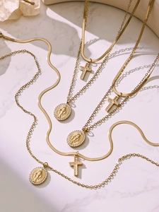 Detail of layered gold necklaces with zircon-encrusted cross and oval Mary medallion