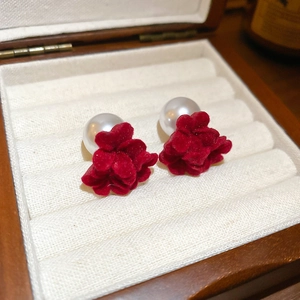 Gros plan de boucles d'oreilles fleur en velours rouge avec perles blanches et boîte