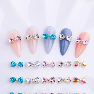 Detailed view of colorful bow-shaped nail charms with assorted crystal colors and metal bases