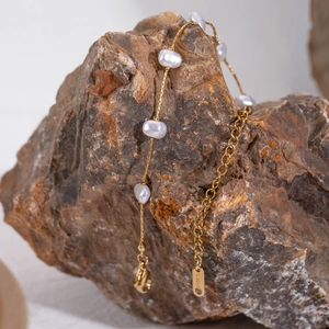 Detailed close-up of gold stainless steel bracelet with baroque pearls on stone