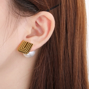Detail view of French vintage square pearl earrings worn by a model in golden U-shape