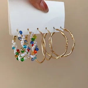 Three pairs of hoop earrings set with colorful beads, gold metal, and textured circles