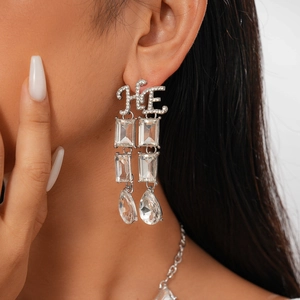 Macro shot of silver drop earrings with HE crystal letters and teardrop pendants