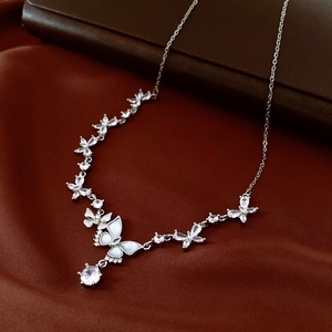 Detailed close-up of zircon butterfly necklace with white shell on luxury red silk fabric