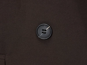 Détail de la texture du tissu marron foncé et bouton noir sur tailleur pour femme
