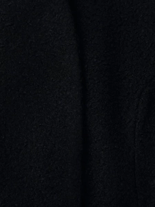 Detailed close-up showing the textured black wool-like fabric of the women's winter coat
