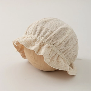 Detailed macro view of the delicate floral lace and soft pleated frills on the baby sun hat