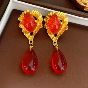 Détail de boucles d'oreilles vintage dorées avec cristaux rouges et pendentifs gouttes