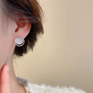 Close-up of elegant silver round earring with white pearl inlay worn by a female model