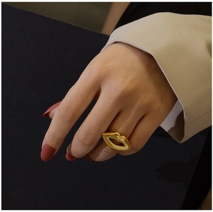 Close-up of a gold lip-shaped ring on a hand with red nails for a stylish fashion statement