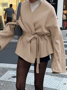Détail d'un manteau beige élégant en laine avec ceinture nouée et manches chauve-souris en ville