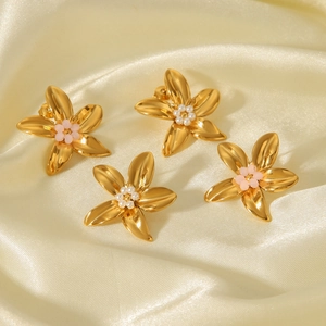 Close-up of four 18k gold flower earrings with pink and white bead centers on silk