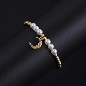 Detail of gold pearl bracelet with zircon moon pendant displayed on a black stand