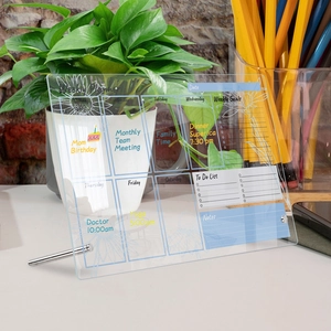 Transparent acrylic weekly planner on desk with metal stands and handwritten notes