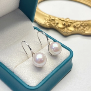 Close-up of elegant freshwater pearl earrings on a teal jewelry box in soft lighting
