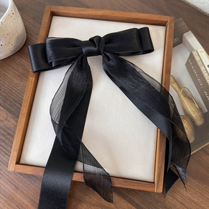 Dettaglio di un grande fiocco nero in tulle su cornice di legno con decori eleganti