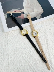 Detail view of quartz watches with black and beige leather straps and gold cases