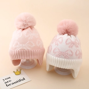 Close-up of knit winter hats with bow patterns and soft pom-poms for girls