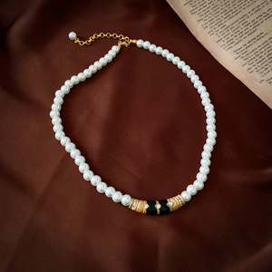 Détail du collier choker vintage avec perles blanches, émail noir et accents dorés