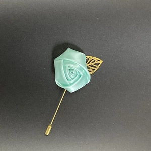 Detail of mint green fabric rose brooch with golden hollow leaf and long stick pin