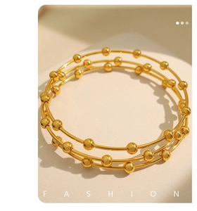 Detail view of triple-layered gold beaded bangle bracelet with a polished metallic finish