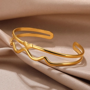 Macro shot of double-layer gold heart bangle on champagne silk with polished wave details