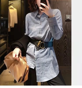 Close-up of black elastic waist belt with gold buckle over blue striped shirt