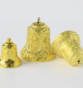 Detailed view of three golden Christmas bells in various sizes with ornate engraved patterns