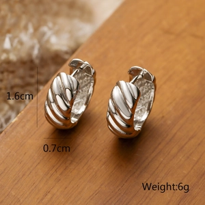 Close-up of silver croissant hoop earrings showing 1.6cm height and 0.7cm width dimensions