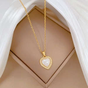 Macro detail of heart pendant necklace with gold chain and shimmering white inlay