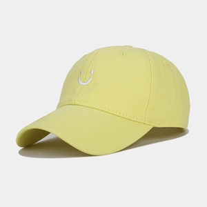 Close-up of yellow cotton baseball cap with white embroidered smiley face and fine stitching
