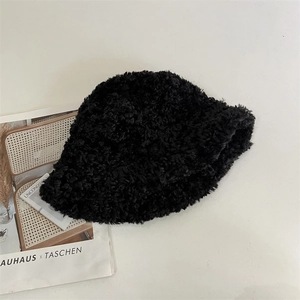 Detail of plush black faux shearling bucket hat on a magazine in a cozy home setting