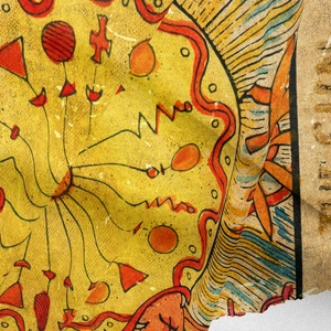 Macro shot of yellow bohemian sun tapestry fabric showing thick woven texture and print