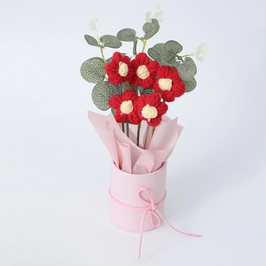 Detail of handmade red crochet bouquet with eucalyptus leaves in pink cylinder gift box