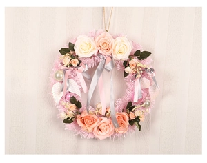 Detail of pink faux rose wreath with champagne flowers, feathers, and festive ribbons
