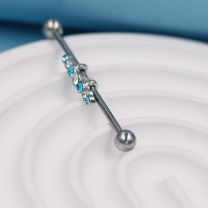 Piercing industriel en argent avec strass bleus et transparents sur un plateau