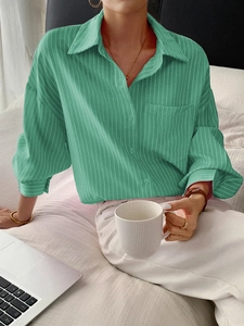 Relaxed fit green striped long sleeve shirt shown in a cozy lifestyle setting with a laptop