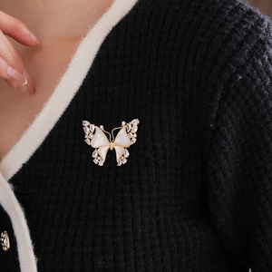 Macro detail of a golden 18k butterfly brooch with shell inlay on black fabric