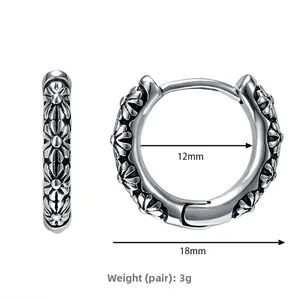 Macro detail of retro silver hoop earrings featuring embossed daisy floral patterns