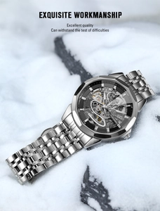 Macro detail of men's skeleton mechanical watch with silver steel strap on a snow background