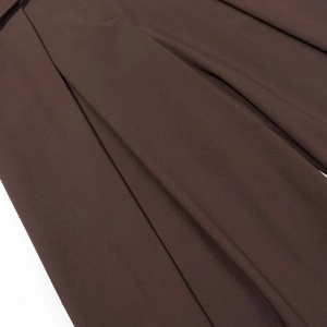 Vue macro détaillée de la texture du tissu plissé marron foncé et des coutures du pantalon