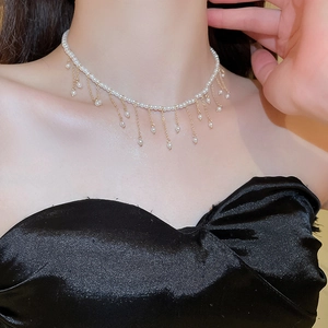 Detail of elegant pearl choker necklace with fringe drop tassels on a model's neck