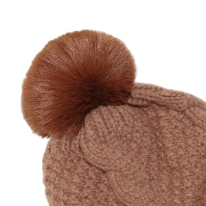 Detail of chunky cable knit pattern and soft faux fur pom-pom on brown winter beanie