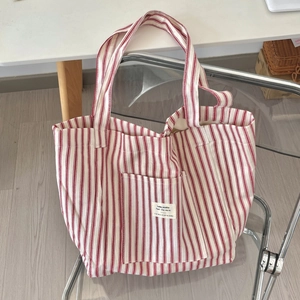Detailed macro view of the red and white striped canvas tote bag showing the front pocket