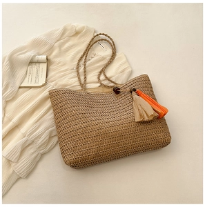 Detail of straw woven tote bag featuring tassel pendants, wooden beads, and rope handle