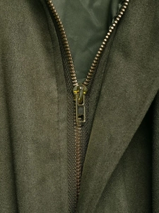 Nahaufnahme eines Metallreißverschlusses auf olivgrünem Wildlederimitat der Jacke