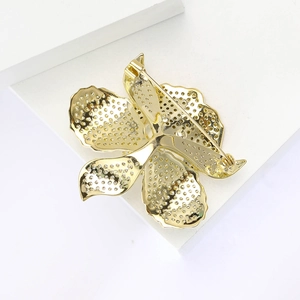 Detailed back view of gold flower brooch showing pin clasp mechanism on white display