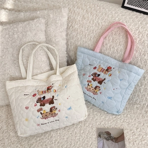 Détail du matelassage en cœur et broderie de chien sur les sacs en coton matelassé